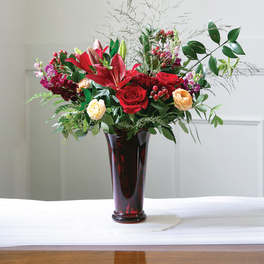 Red and peach flowers arranged in a tall glass vase