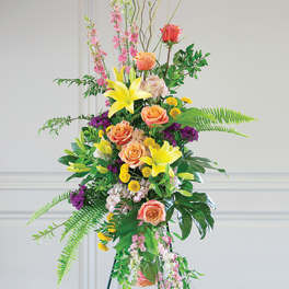 Tall floral standing arrangement with roses, lilies, and mixed blooms