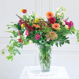 Mixed bouquet of bright flowers in a clear glass vase