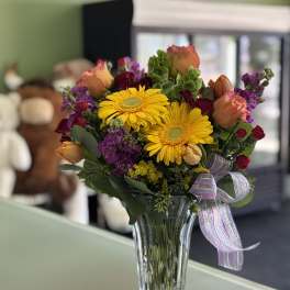 Bouquet of yellow gerbera daisies and mixed roses in a glass vase
