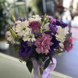 Bouquet of white daisies, purple blooms, and pink carnations in a glass vase