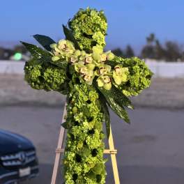 Green floral cross on an easel with pale orchids