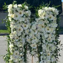 Large white floral standing spray shaped like a letter M on an easel