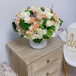 White and blush rose arrangement in a white vase