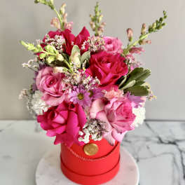 Pink and red rose bouquet in a red hat box on a round base