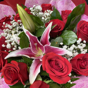 Bouquet of red roses and a pink lily with white filler flowers