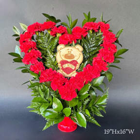 Heart-shaped carnation arrangement with a teddy bear topper
