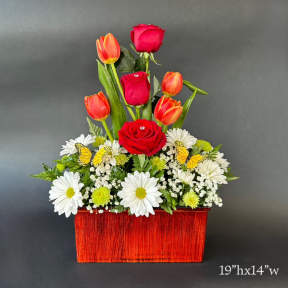 Red roses and orange tulips in a red rectangular container with white daisies