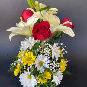 Red roses and white lilies arranged with yellow and white daisies