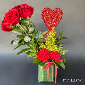 Red roses and carnations in a green vase with a glitter heart pick