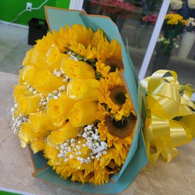 Bouquet of yellow roses and sunflowers wrapped in blue paper with a yellow ribbon
