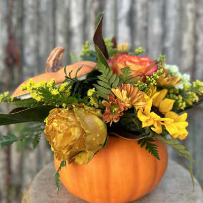 Fall flower arrangement in a pumpkin container with yellow and orange blooms