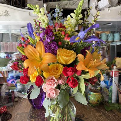 Colorful mixed bouquet in a clear glass vase with roses and lilies