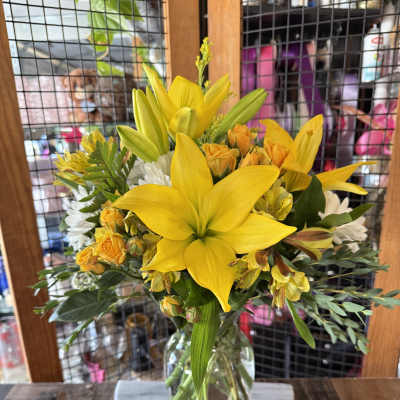 Yellow lilies and small orange roses in a glass vase
