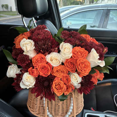 Basket arrangement of orange, white, and burgundy roses and mums