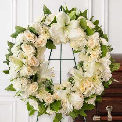 White floral wreath with roses and lilies on a stand