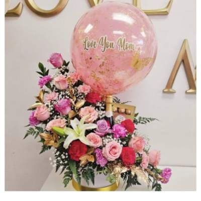 Pink rose arrangement with a large balloon reading Love You Mom