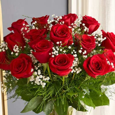 Red roses arranged in a clear glass vase with baby's breath