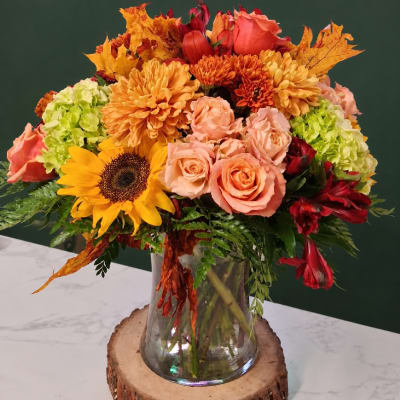 Autumn bouquet of roses, sunflowers, and mums in a glass vase