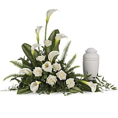 White calla lilies and roses arranged around a white cremation urn.