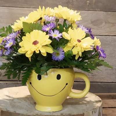 Yellow and purple flowers in a smiley-face mug vase