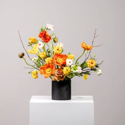 Orange and yellow floral arrangement in a black vase