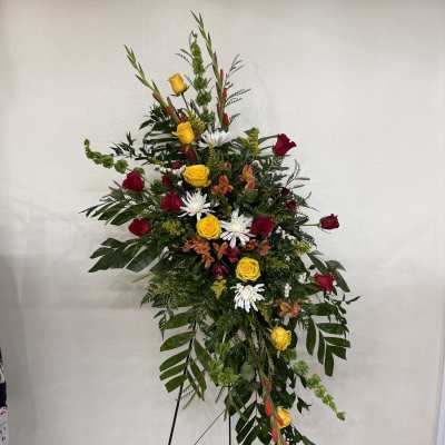 Tall standing floral spray with red and yellow roses and white daisies