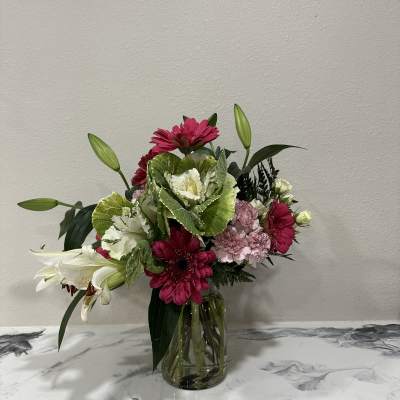 Mixed pink and white flowers arranged in a clear glass vase