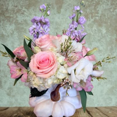 Pink and white floral arrangement in a white pumpkin container