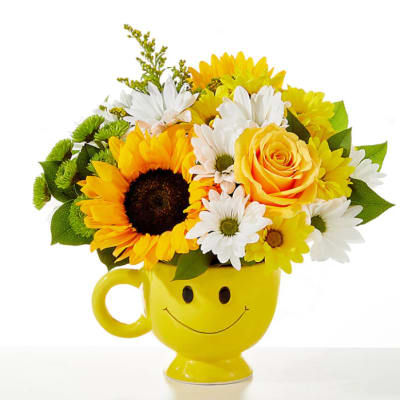 Yellow smiley-face mug holding sunflowers and daisies