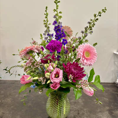 Mixed pink and purple flower arrangement in a textured glass vase