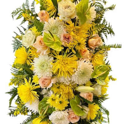 Tall yellow and white standing floral spray with roses, mums, and lilies on an easel