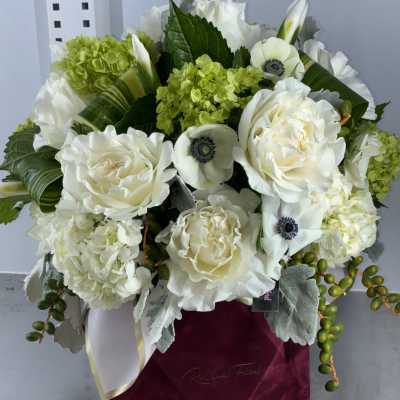 White roses and green hydrangeas in a burgundy box
