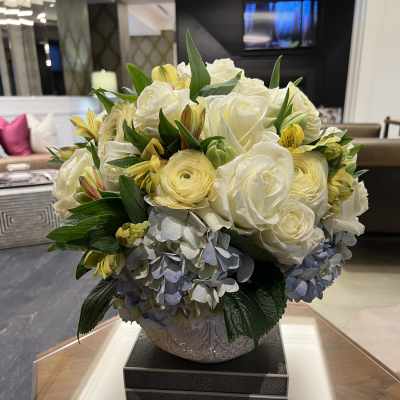White roses and yellow flowers arranged in a decorative vase