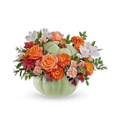 Orange and white flowers arranged in a pale green pumpkin vase