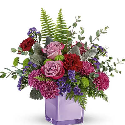 Purple and pink flower arrangement in a lavender glass vase