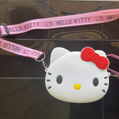 Hello Kitty face-shaped pouch with a pink strap on a dark surface
