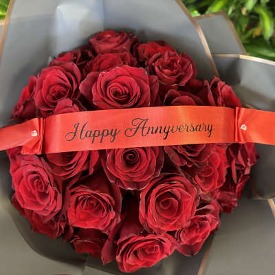 Bouquet of red roses wrapped with a Happy Anniversary ribbon