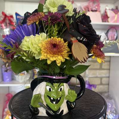 Colorful bouquet in a Halloween witch mug with a decorative witch face