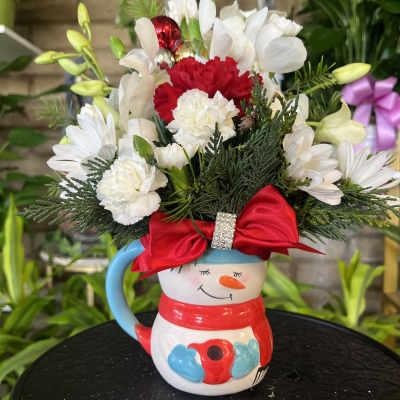 Snowman mug filled with white and red flowers and a red bow