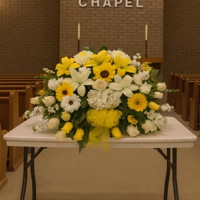Yellow and white floral arrangement on a table in a chapel
