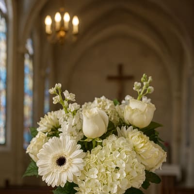 White floral arrangement in a glass vase with a ribbon