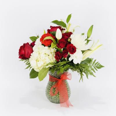 Red roses and white flowers in a glass vase with a red ribbon