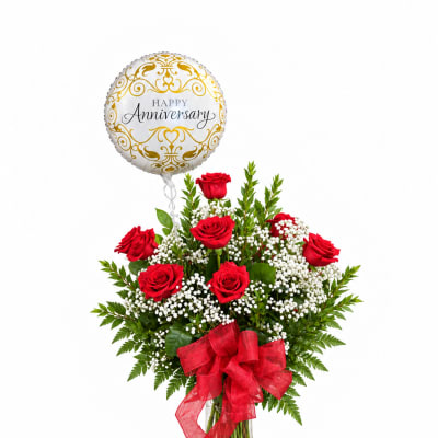 Red roses in a glass vase with a gold anniversary balloon