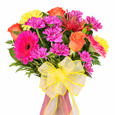 Mixed bouquet of pink, orange, and yellow flowers in a pink vase with a yellow bow