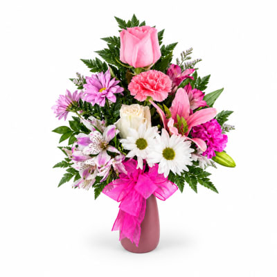 Pink and white mixed bouquet in a mauve vase with a bright ribbon