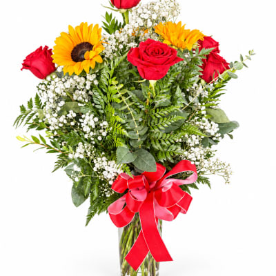 Bouquet of red roses and yellow sunflowers in a glass vase with a red ribbon