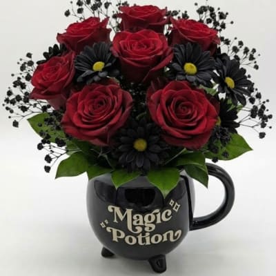 Red roses and black daisies in a black mug-shaped vase