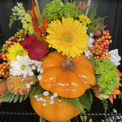 Autumn floral arrangement with a bright orange pumpkin centerpiece