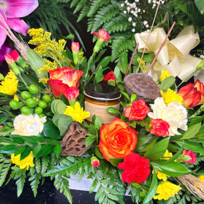 Mixed bouquet with roses, carnations, and yellow blooms around a candle jar